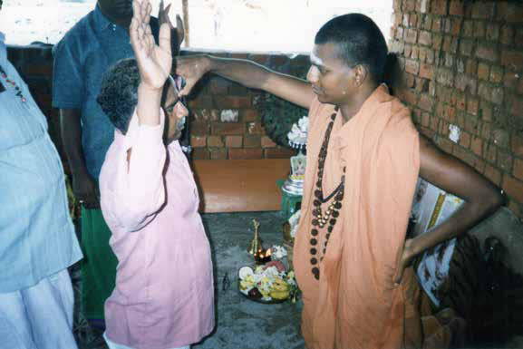 The SPH blessing and healing devotees inside the simple thatched roof structure